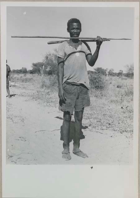 Man with a beard standing and holding an assegai and a club
