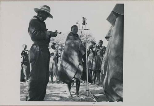 Rose, a soloist, and Kernel Ledimo using microphone, and women standing and clapping