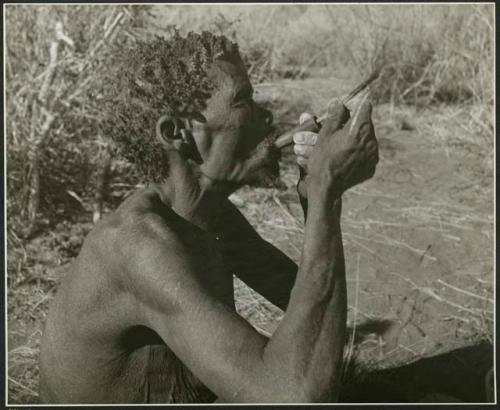 "Smoking": "Old /Gaishay" pushing tobacco down his pipe, profile (print is a cropped image)