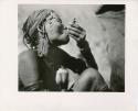 "Smoking": Woman smoking a pipe made from a cartridge (print is a cropped image)