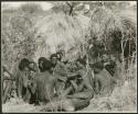 [No folder title]: Group of Ju/'hoansi telling stories including (left to right) "Lame ≠Gao" seen from behind, ≠Gao (Khwo//o-/Gasa's husband), "Gao Medicine," unidentified person seen from behind, ≠Toma, !Naishi, "Old Xama" with her hands over her head, "Gao Helmet" in profile, "Old Demi" lying down, "Crooked /Qui," Gao (Debe's son, Zuma's husband), ≠Toma (!Naishi's son), and Zuma (Gao's wife) (print is a cropped image)