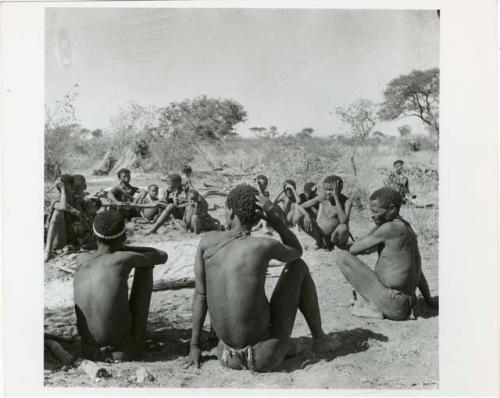 [No folder title]: "Gao Hunchback" with his hand to his face, sitting with his band, his extended family (print is a cropped image)