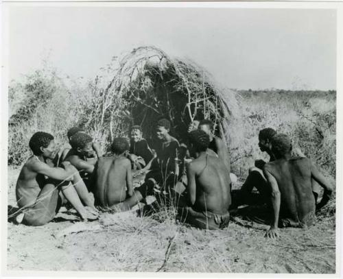 [No folder title]: Group of people sitting in front of a skerm and telling stories, including Zuma (daughter of "Old Xama," wife of Gao), Gao (son of Debe, headman of Band 24 in Cho/ama), and /Qui (brother of "Gao Helmet") (print is a cropped image)