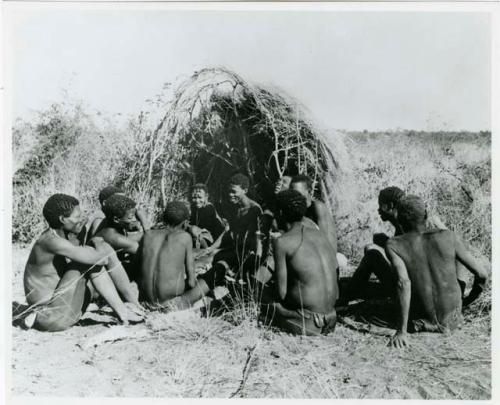 [No folder title]: Group of people sitting in front of a skerm and telling stories, including Zuma (daughter of "Old Xama," wife of Gao), Gao (son of Debe, headman of Band 24 in Cho/ama), and /Qui (brother of "Gao Helmet") (print is a cropped image)