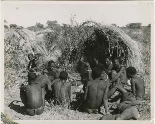 [No folder title]: Group of Ju/'hoansi telling stories including "Lame ≠Gao" seen from behind, ≠Gao (Khwo//o's-/Gasa's husband), Gao Medicine, an unidentified person, ≠Toma, !Naishi, "Old Xama" holding a child, "Gao Helmet," "Old Demi" lying down, "Crooked /Qui," Gao (Debe's son, Zuma's husband), ≠Toma (!Naishi's son), and Zuma (Gao's wife) (print is a cropped image)