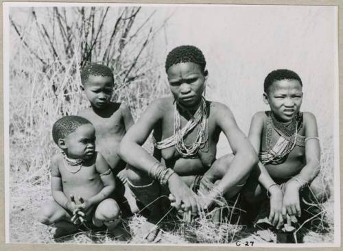 "1952-53, G23-G27": Di!ai (wife of "/Qui Guide") sitting with //Ao's three children, /Qui, Di//khao and !Ungka (who was engaged to /Gunda, son of "Old ≠Toma" and /Gam) (print is a cropped image)