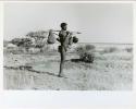 [No folder title]: /Ti!kay carrying bags on a carrying stick and an assegai, with Gautscha Pan in the background (print is a cropped image)