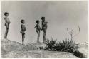 "Children in groups": Four boys standing in profile, silhouetted against the sky (print is a cropped image)