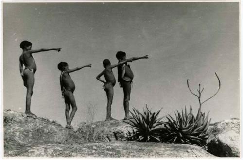 "Children in groups": Four boys standing in profile, silhouetted against the sky (print is a cropped image)