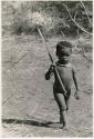 [No folder title]: Boy walking, holding a stick (print is a cropped image)