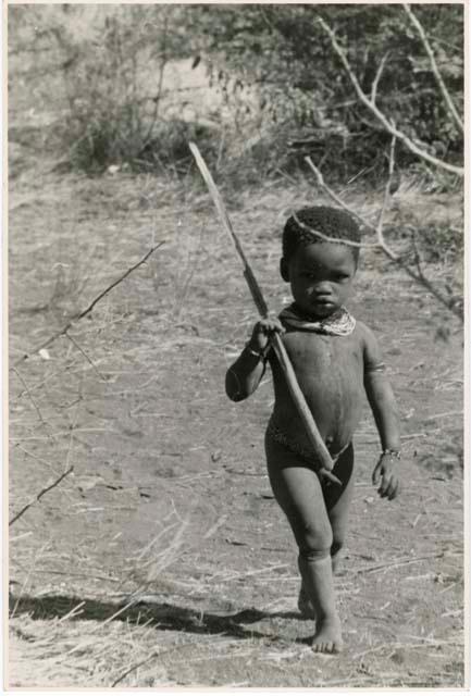 [No folder title]: Boy walking, holding a stick (print is a cropped image)