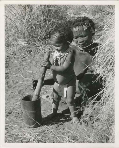 "≠Toma's sister !Ungka from Kai Kai, Her da. [daughter] Sa≠gai, she is wife of /Ga[i]shay": !Ungka (≠Toma's sister) and her daughter, Sa≠gai, who is playing with a mortar and pestle (print is a cropped image)