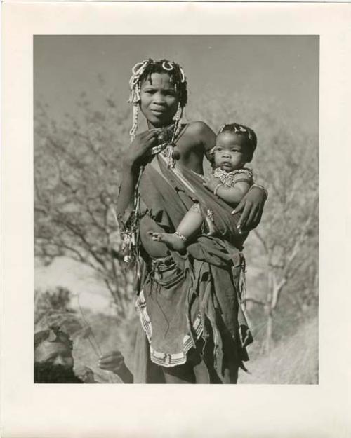 [No folder title]: Woman from /Ti!kay's group standing and carrying her baby (print is a cropped image)