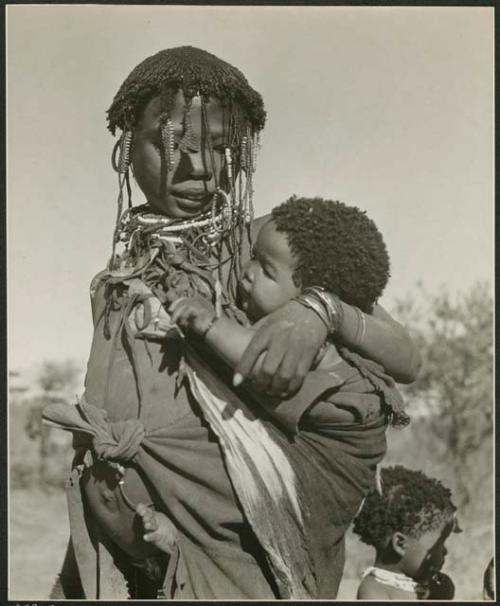 "Carrying children": Woman carrying a baby (print is a cropped image)