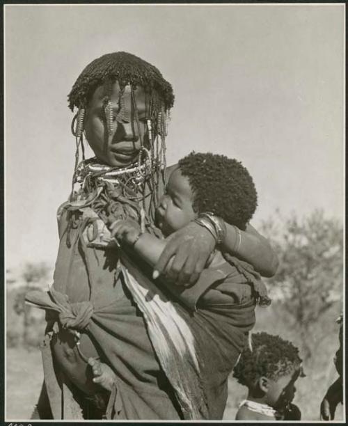 "Carrying children": Woman carrying a baby (print is a cropped image)