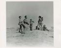 "Boys and girls playing together": Boys and girls dancing on a ledge by a waterhole, one boy playing a //guashi