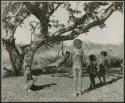 "Groups, Girls, Boys and Girls": Children playing under a tree with a swing they made from leather (print is a cropped image)