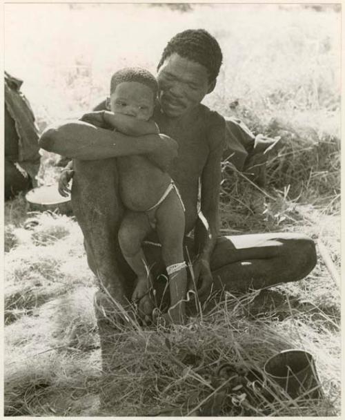 "Fathers carrying children": "Gao Medicine" sitting and holding Debe against his knee (print is a cropped image)