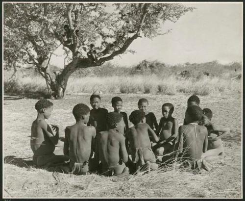 "Porcupine or Axe and Assegai [game]": Group of men and boys playing !ó'm!hú / !’Om g!xuni / ’Ai kota !U!u g!xuni / N!aih //’an (the porcupine game, also known as the axe game, assegai game or war game), including "≠Gao Lame," /Gunda with a feather, ≠Gao (son of Gau and Be of Band 2) and Tsamgao (son of ≠Toma, Band 1) (print is a cropped image)