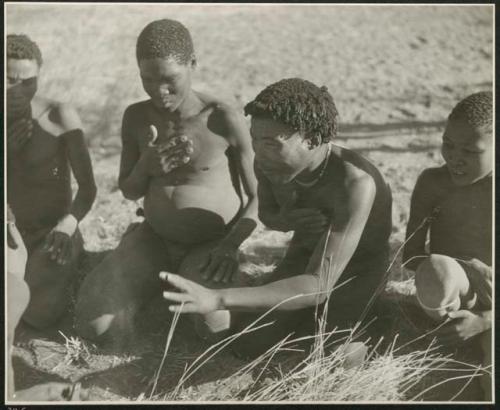 "Porcupine or Axe and Assegai [game]": Men and boys playing !ó'm!hú / !’Om g!xuni / ’Ai kota !U!u g!xuni / N!aih //’an (the porcupine game, also known as the axe game, assegai game or war game), including //Ao (husband of Khuan//a, daughter of /Gaishay of Band 4), who is stretching out his hand (print is a cropped image)