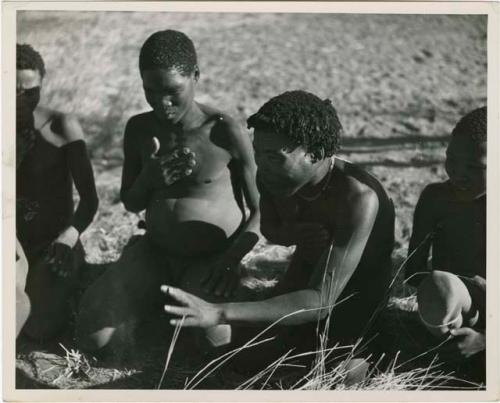 "Porcupine or Axe and Assegai [game]": Men and boys playing !ó'm!hú / !’Om g!xuni / ’Ai kota !U!u g!xuni / N!aih //’an (the porcupine game, also known as the axe game, assegai game or war game), including //Ao (husband of Khuan//a, daughter of /Gaishay of Band 4), who is stretching out his hand (print is a cropped image)