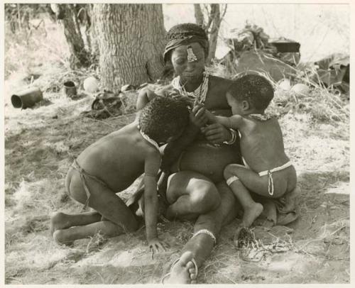 "Nursing": Di!ai sitting in a werft with a cord of beads in her mouth while nursing /Gaishay and Debe (print is a cropped image)