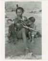 "Nursing": Di!ai nursing Debe who clutches a toy bow and arrow (print is a cropped image)