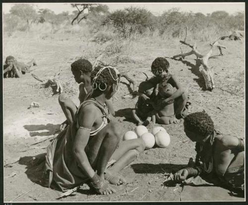 "Babies nursing": !U, !Ungka, Di!kai (≠Toma's sister) and "≠Gao Lame" sitting, with five ostrich egg shells on the ground next to them (print is a cropped image)