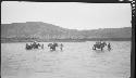 People fording river with mules