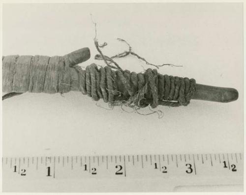 End of Oukwane's bow, close-up showing knot, with a ruler for measurement (print is a cropped image)