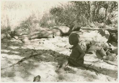 Oukwane and an unidentified person sleeping, with N!whakwe sitting near them (print is a cropped image)