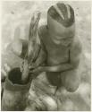 "Visiting boy" pounding something in mortar with pestle (print is a cropped image)