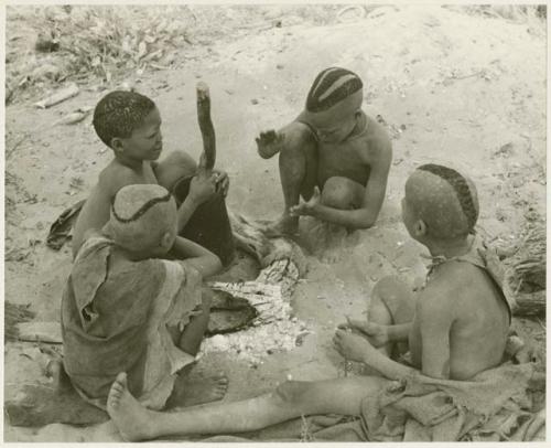 Boys of Oukwane's group and "visiting group" sitting by a fire (print is a cropped image)