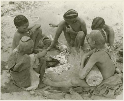 Boys of Oukwane's group and "visiting group" sitting by a fire (print is a cropped image)