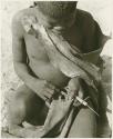 Man sewing, using an awl and a piece of leather (print is a cropped image)