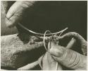 Person sewing, close-up of hands making knot (print is a cropped image)