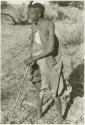 /Twikwe standing leaning on digging stick, full figure (print is a cropped image)