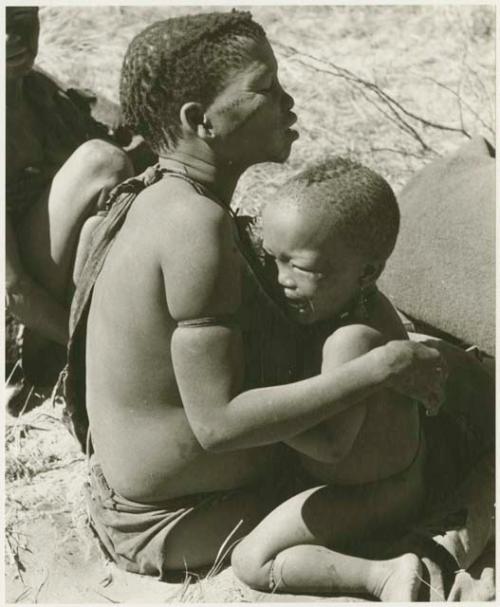 Tsekue holding N!whakwe, who is crying (print is a cropped image)