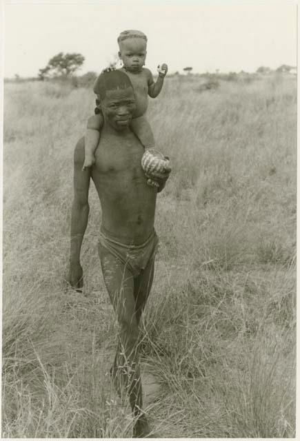 Man carrying a child on his shoulders (print is a cropped image)