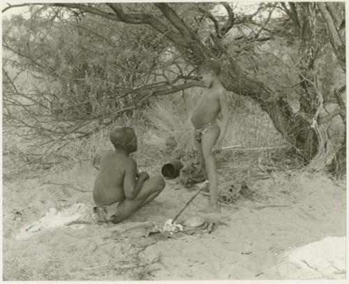 Oukwane seated, with !Outkabe standing beside him in their werft (print is a cropped image)