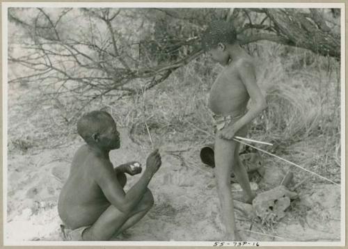 Oukwane seated, with !Outkabe standing beside him in their werft (print is a cropped image)