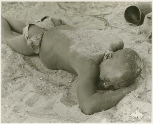 Oukwane lying on his stomach, with sand sprinkled on his back (print is a cropped image)