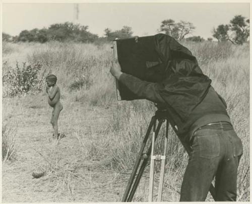 Boy standing, with John Marshall filming him (print is a cropped image)