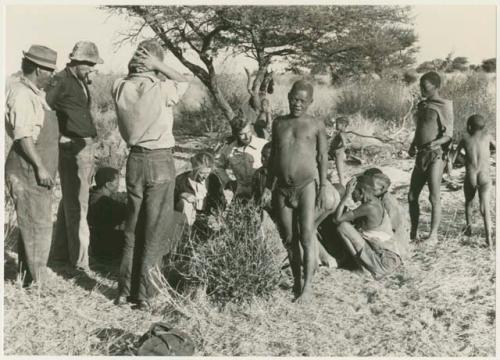 Group of people, including Oukwane and !Gai, being interviewed by Lorna Marshall and Elizabeth Marshall, with Casper Kruger, Kernel Ledimo, Wilhelm Camm, John Marshall, and Daniel Blitz watching (print is a cropped image)