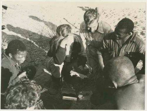 People receiving gifts from Lorna Marshall, surrounded by Dabe, Daniel Blitz, Kernel Ledimo, Oukwane, and Elizabeth Marshall Thomas (print is a cropped image)