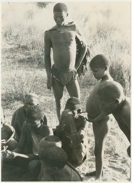 Oukwane's group receiving presents from the expedition team, with !Gai and Oukwane watching (print is a cropped image)