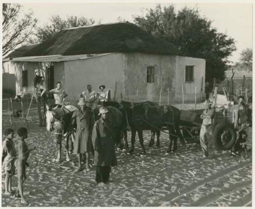 Theunis Berger's house with a group of people, including Theunis Berger and Marguerita Ammann, gathered in the foreground (print is a cropped image)