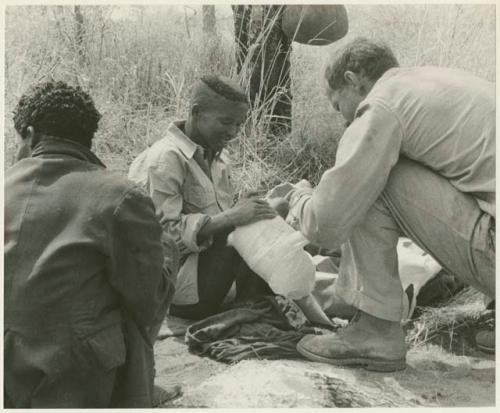 William Donnellan bandaging "/Qui Hunter's" leg with ≠Toma's assistance (print is a cropped image)