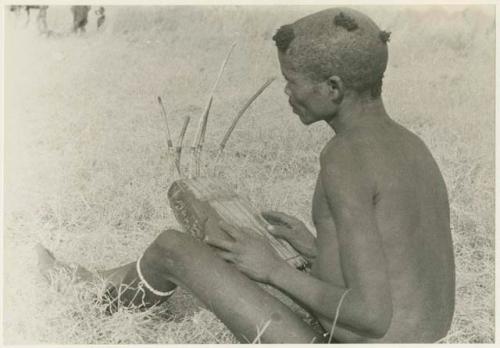 "/Gao Music" sitting with a //guashi, seen from behind (print is a cropped image)