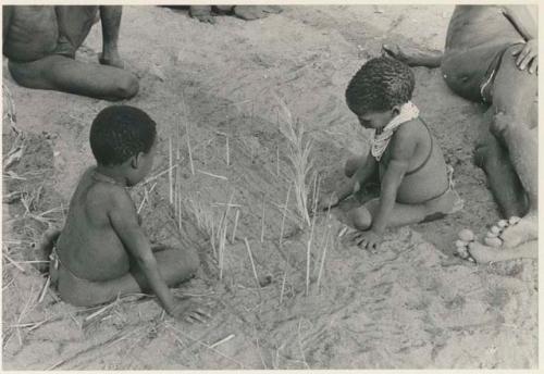 Two boys looking at the sticks for constructing a playhouse (print is a cropped image)